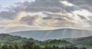 This is a signed limited edition print of an original soft pastel painting by artist Michael Howley. The subject of the painting is a panoramic landscape of Pendle Hill with the rays of the sun breaking through the clouds above. The hill and foreground fields and trees are slightly misty. The palette is soft blue-greys and pastel shades of muted greens.