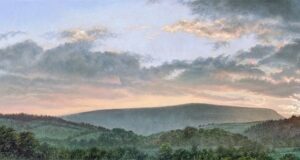 This is a signed limited edition print of an original soft pastel painting by artist Michael Howley. The subject of the painting is a panoramic view of Pendle Hill with the sun setting to the right and soft grey and pink clouds floating across a pastel blue sky. The hill is in soft grey-greens and the foreground is in darker muted greens with a hint of mist. The sun glows across the tree tops to the right.