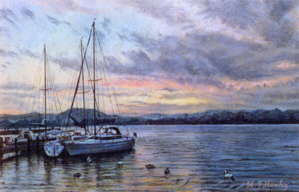 This is a signed limited edition print of an original soft pastel painting by artist Michael Howley. The subject of the painting is boats moored on Windermere set against an evening sky with soft grey clouds and pastel colours of blue and pink which are reflected in the ripples of the Lake.