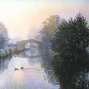 This is a signed limited edition print of an original soft pastel painting by artist Michael Howley. The subject of the painting is a tranquil misty morning scene of the canal with a bridge which is surrounded by trees which soften into the distant mist. Colours in the atmospheric sky are creamy whites, pale pinks, peaches, blues and purples which are reflected in the calm waters. Two ducks float serenely across the surface.